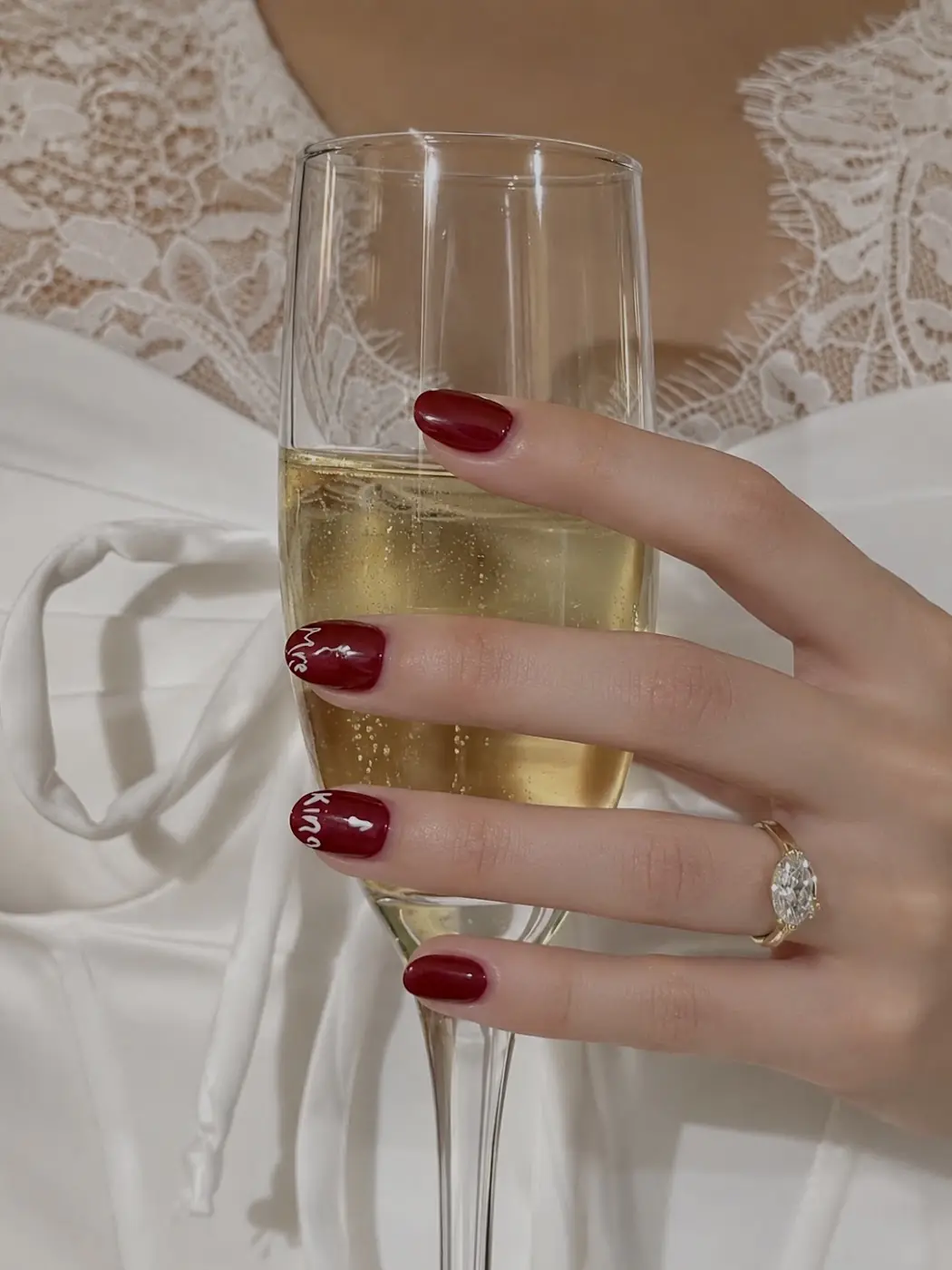 Glossy red nails holding a glass of champagne