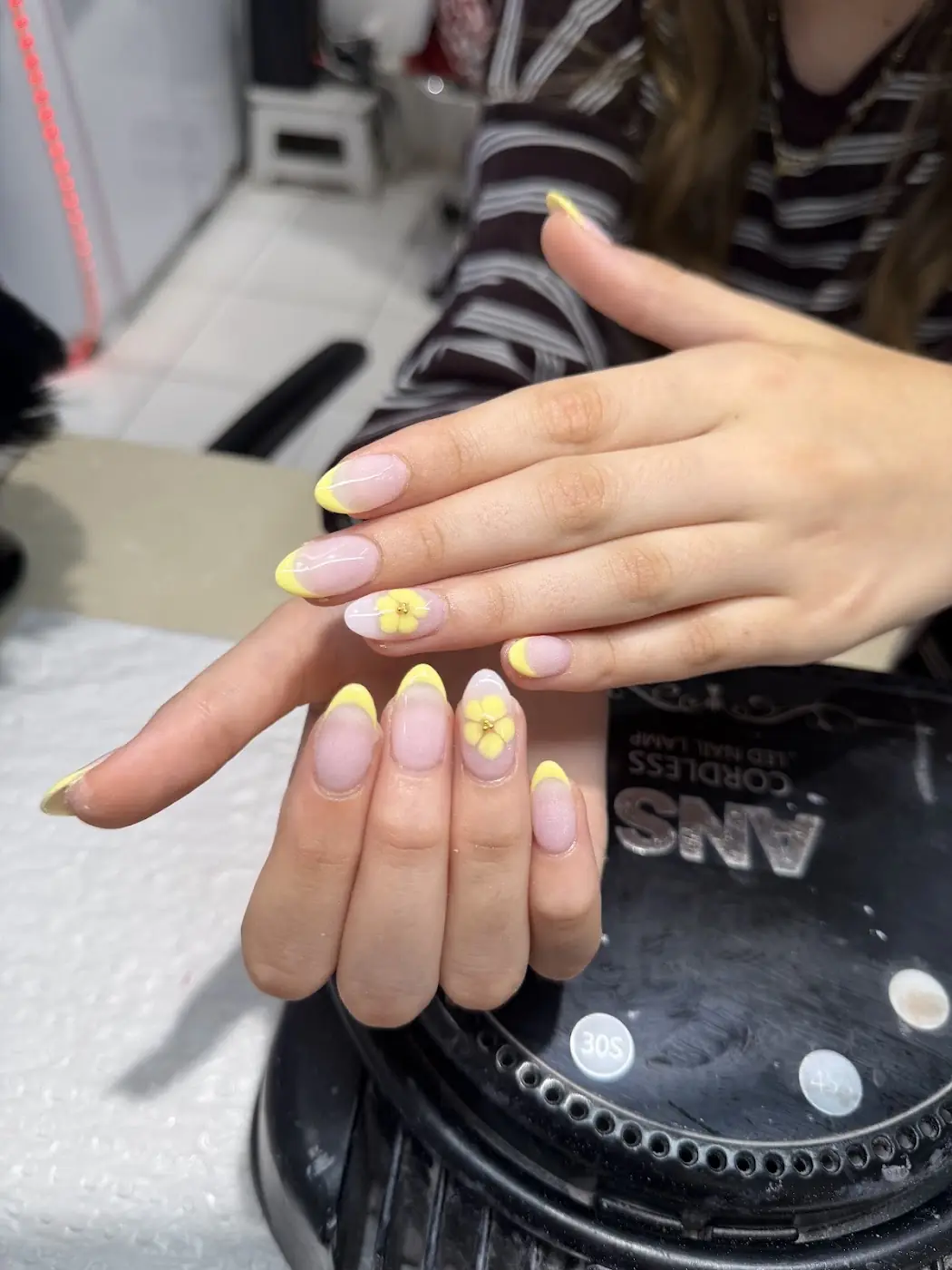 Soft pink nails with a yellow flower accent